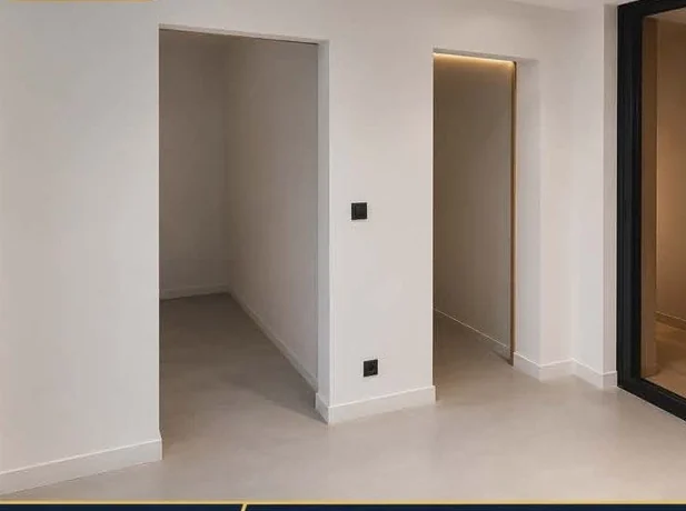 Même pièce après rénovation ACJ : murs blancs lissés, sol fini, éclairage LED intégré