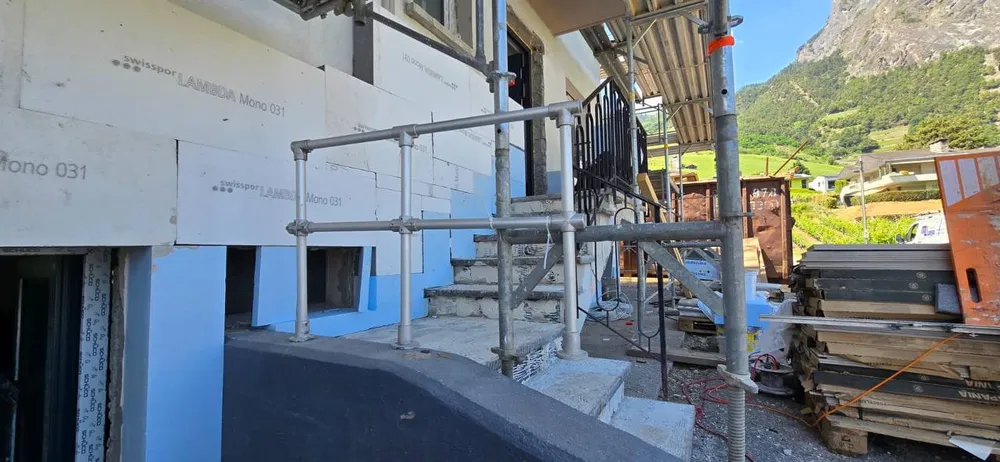 Façade en rénovation avec échafaudage, dans un cadre de montagne valaisan